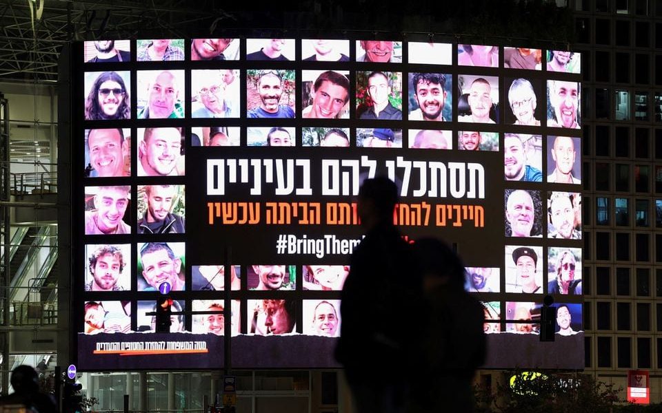 A screen displays photos of people who were abducted by Hamas gunmen during the October 7 attack on Israel, in Tel Aviv, Israel, November 27, 2023. REUTERS/Athit Perawongmetha/File Photo