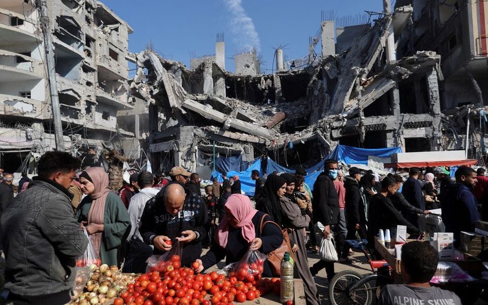 Palestinians shops in an open-air market near the ruins of houses and buildings destroyed in Israeli strikes during the conflict, amid a temporary truce between Hamas and Israel, in Nuseirat refugee camp in the central Gaza Strip November 30. REUTERS/Ibraheem Abu Mustafa