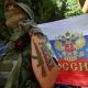File photo: A participant stands next to a Russian state flag at an exhibition showcasing volunteers' product range, manufactured to supply the needs of service members involved in Russia's military campaign in Ukraine, in Yevpatoriya, Crimea, July 29, 2023. A tattoo reads: "Russia". REUTERS/Alexey Pavlishak/File photo