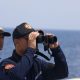 A Philippine Coast Guard personnel looks through a binocular while conducting a resupply mission for Filipino troops stationed at a grounded warship in the South China Sea, October 4, 2023. REUTERS/Adrian Portugal/File Photo
