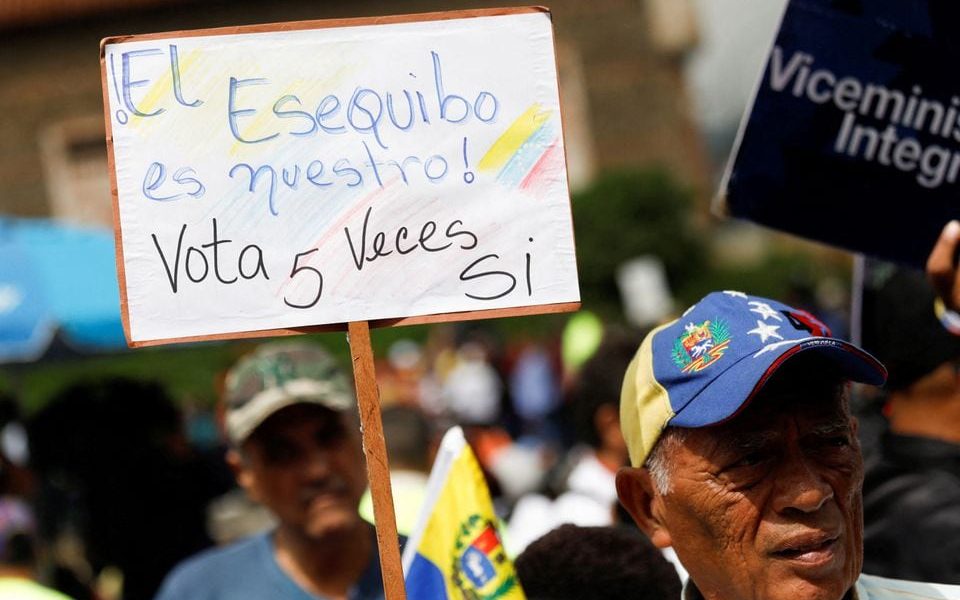 A government supporter holds a sign that reads: “The Essequibo is ours, vote YES 5 times” while participating in an event to collect signatures in support of a referendum over Venezuela's rights to the potentially oil-rich region of Esequiba in Guyana, in Caracas, Venezuela November 15, 2023. REUTERS/Leonardo Fernandez Viloria/File Photo