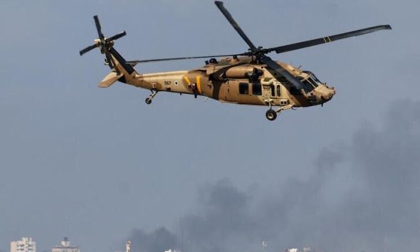 An Israeli military helicopter flies as smoke rises over Gaza, amid the ongoing conflict between Israel and the Palestinian Islamist group Hamas, as seen from southern Israel, December 6, 2023. REUTERS/Athit Perawongmetha