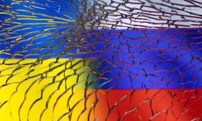 Ukraine and Russian flags are seen through broken glass in this illustration taken March 1, 2022. REUTERS/Dado Ruvic/Illustration/File Photo
